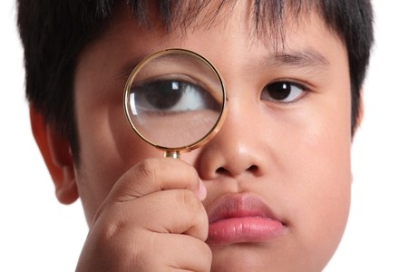 Child with magnifying glass isolated on white background の写真素材