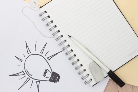 Hand-drawn light bulb and pen with spiral notebook