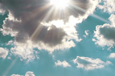 Background of blue sky with sun rays and cloudsの写真素材
