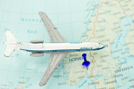 Travel to Norway concept - toy airplane on top of norway map and a push pin