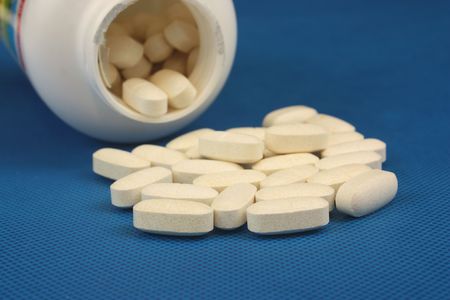 Bottle of white pills spilled on a blue clothの写真素材