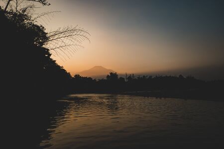 Slamet mountains silhouettes sunset panorama and river reflectionの写真素材