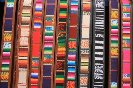 Colorful handmade cloth and leather belts for sale at the outdoor craft market in Cotacachi, Ecuadorの写真素材