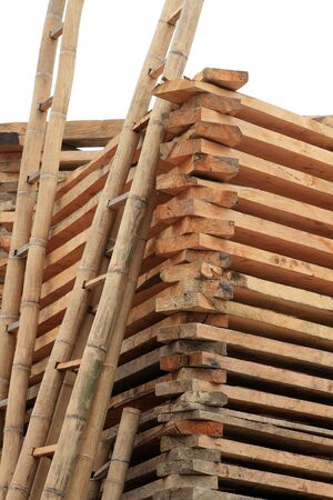 A stack of wood and handmade bamboo ladders for sale at an outdoor lumber yard and sawmill in Cotacachi, Ecuadorの写真素材