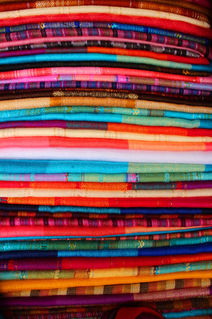 Bright handmade blankets in a variety of patterns and colors for sale at the outdoor craft market in Otavalo Ecuadorの写真素材