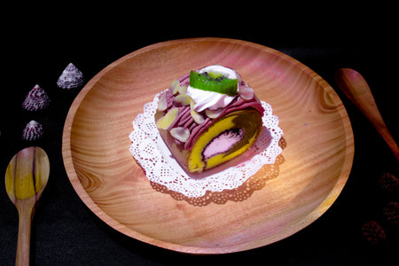 Indonesian sweet cakes served on natural wooden plate and spoon with black background highlighting traditional dessert texture and authentic tropical food styleの写真素材