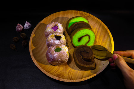 Indonesian sweet cakes served on natural wooden plate and spoon with black background highlighting...