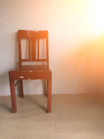 Old chair against old wall background with orange sunlightの素材