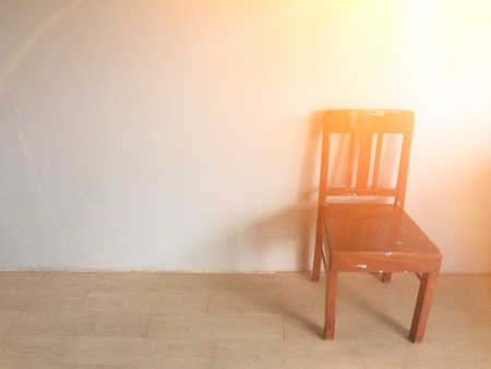 Old chair against old wall background with orange sunlightの素材