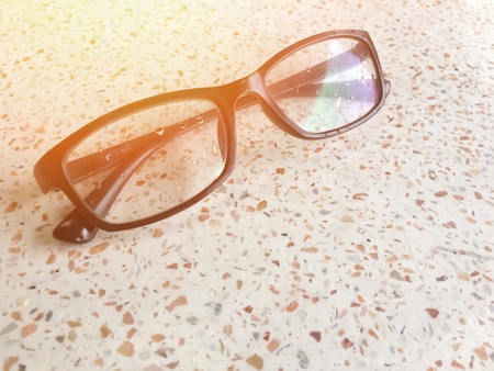 Black glasses placed on marble with light orange light.の素材