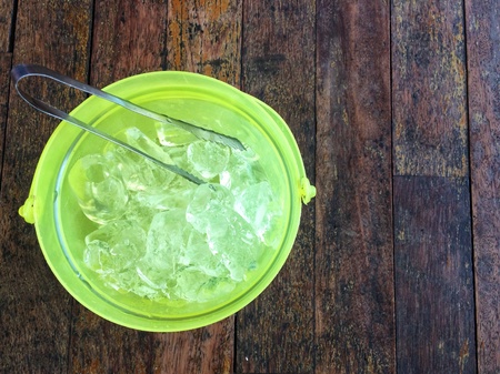 Ice with tongs on wood background with copy space