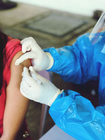 Picture of a doctor injecting covid-19 vaccination on the arm of people who come to receive service,...