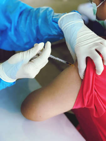 Picture of a doctor injecting covid-19 vaccination on the arm of people who come to receive service,...