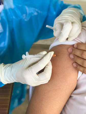 Picture of a doctor injecting covid-19 vaccination on the arm of people who come to receive service, coronavirus disease (covid-19)の写真素材
