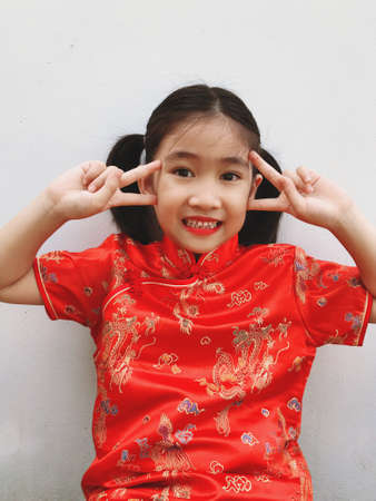 Girl tying her hair on both sides in red dress for Chinese New Year, her made an emotional expression in each of her feelingsの写真素材