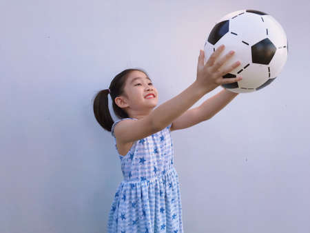 A girl with two hair tied up in a blue star-patterned outfit holding a soccer ball.