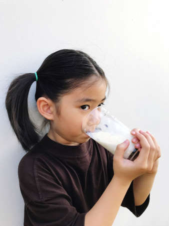 Girl holding a glass of ready-to-drink milk for a healthy body, white backgroundの写真素材