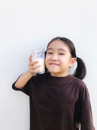 Girl holding a glass of ready-to-drink milk for a healthy body, white backgroundの写真素材