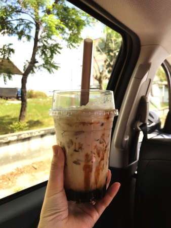 Show your hand holding a coffee cup while driving, adding freshness while driving.の写真素材