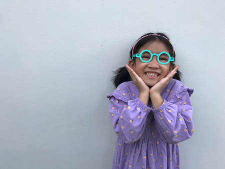 A cute girl wearing a purple dress wearing blue glasses makes a cute and bright pose.の写真素材