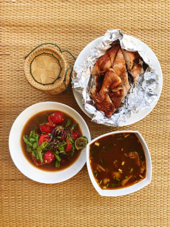 Papaya Salad with Long Beans, Grilled Chicken and Spicy Beef Soup It is Isan food that is placed on a mat.の写真素材