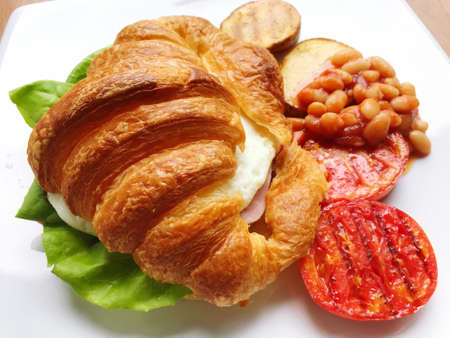 Breakfast made with eggs and croissant, laid out and decorated with red tomatoes for breakfast with...
