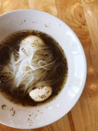 A picture of a cup of Thai noodle placed on a table in a restaurant