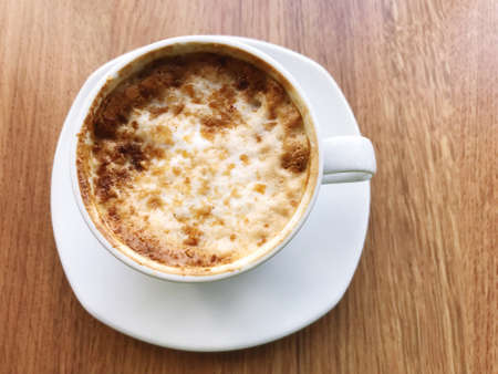 A cup of cappuccino is placed on the table in a cafe atmosphere.の写真素材