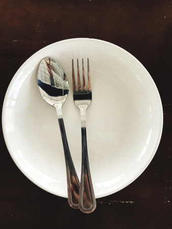 Top view of a plate with a spoon and fork placed on top. and placed on the dining table.の写真素材