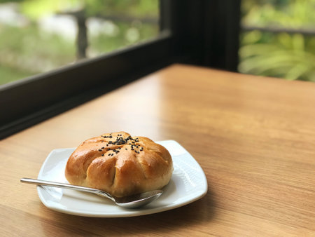 Delicious red bean-filled bread on a white plate in a cozy restaurant or cafe.の写真素材