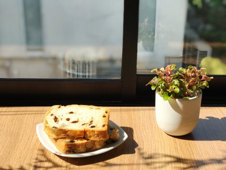 Sliced bread with raisins on white plate placed on wooden table in minimalist cafeの写真素材