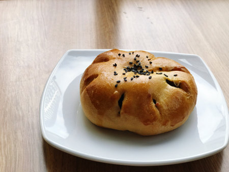 Buns filled with red bean paste topped with black sesame seeds are placed on a white plate on a...