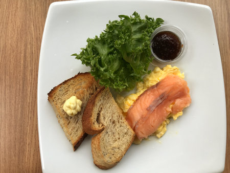 A breakfast made of eggs, salmon, vegetable and toasted bread is laid out and decorated in a white coffee cup for breakfast.の写真素材