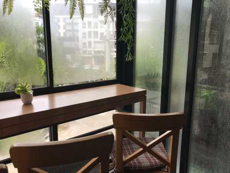 Wooden table and chair in coffee shop with rain drops on window