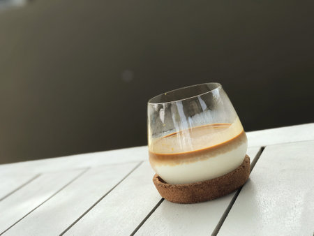 Panna cotta with caramel sauce in a glass on a wooden tableの写真素材