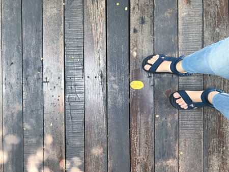 Female feet in slippers on a wooden deck. Top view.