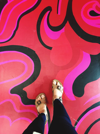 Selfie of a girl's feet in sandals on a graffiti wall