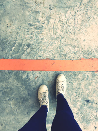 Selfie of feet in sneakers on concrete floor with red line.の写真素材