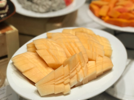 Mango slices on white plate in buffet restaurant, closeup of photoの写真素材