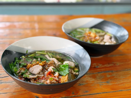 Thai noodle with pork and vegetable in bowl on wooden tableの写真素材