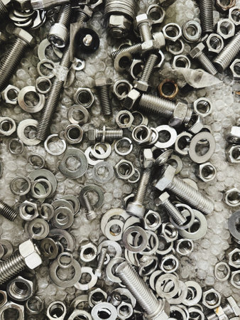 Metal bolts, nuts and washers on grey background. Top view.