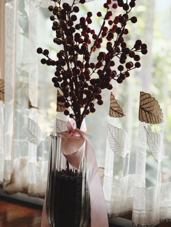 Bouquet of red berries in a glass vase on the windowsill