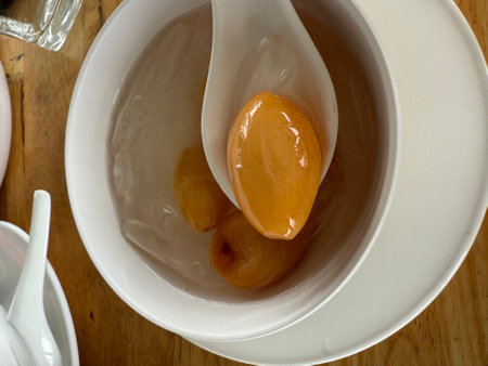 Dried apricots in a white spoon on a wooden table