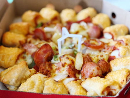 Close up of a box of pizza with sausage, cheese and vegetables