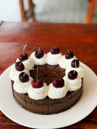 Chocolate cake with whipped cream and cherries on wooden table.の写真素材