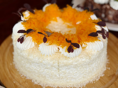 Cream cake with orange on top decorated with leaves and flowers.の写真素材