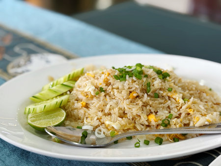 Fried rice with fried corn and cucumber on a white plateの写真素材
