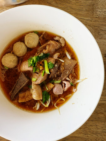Thai noodle soup with pork and meat ball in white bowl