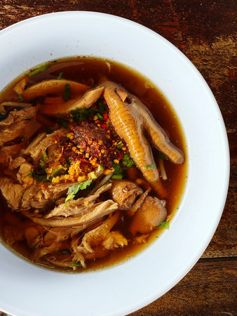 spicy soup with duck in a white bowl on wooden table