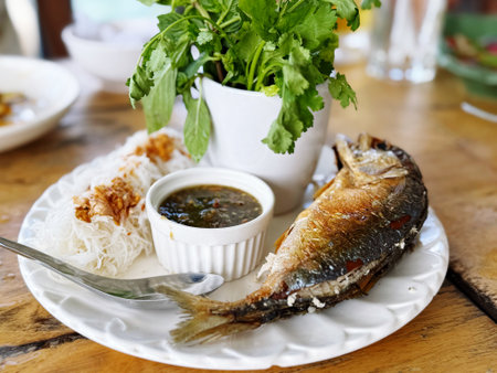 Fried mackerel with sweet and sour sauce on wooden table